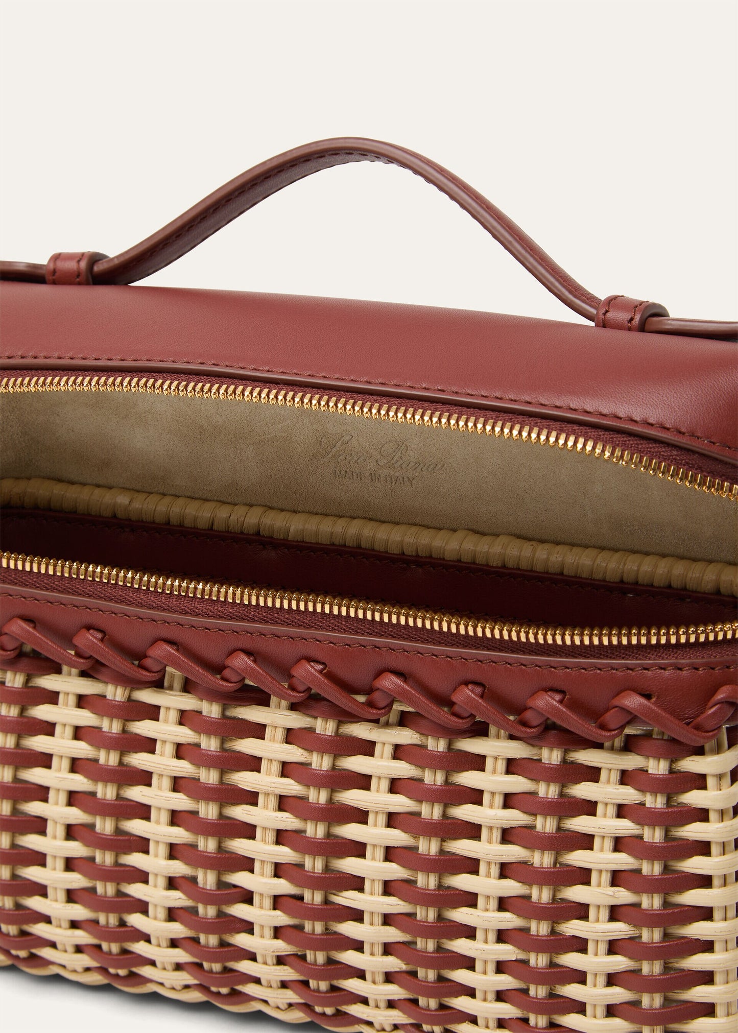 Wicker and calfskin pouch close-up of interior lining and gold zipper trim.
