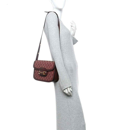 Gucci mini shoulder bag on person, burgundy monogram canvas with leather strap