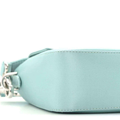 Blue satin baguette bag close-up of curved front and circular side hardware