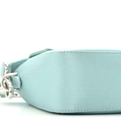 Blue satin baguette bag close-up of curved front and circular side hardware