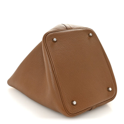 Tan leather tote close-up with stud feet and structured triangular base