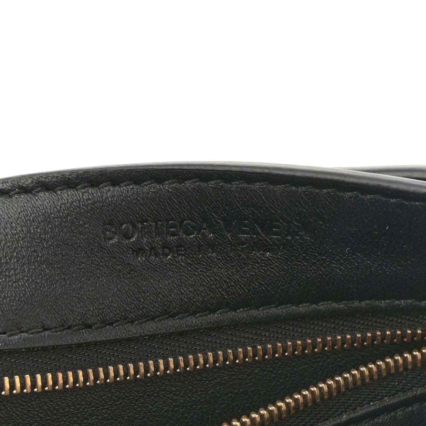 Black leather bag interior edge with gold zipper teeth and stitched seam