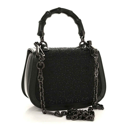 Black mini handbag with chain strap and top handle, textured surface and front clasp.