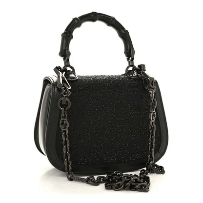 Black mini handbag with chain strap and top handle, textured surface and front clasp.