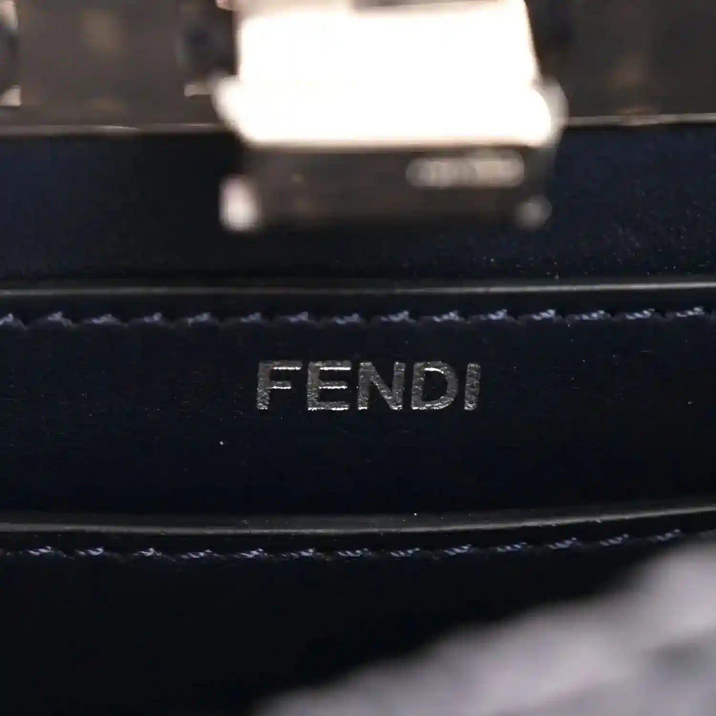 FENDI logo embossing on dark leather lining with stitched trim