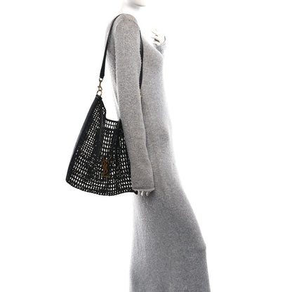 Black shoulder bag with netted raffia texture and leather shoulder strap, side view