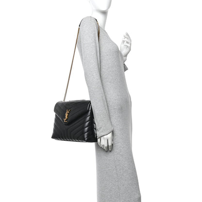 Black quilted calfskin satchel with gold chain strap, worn crossbody