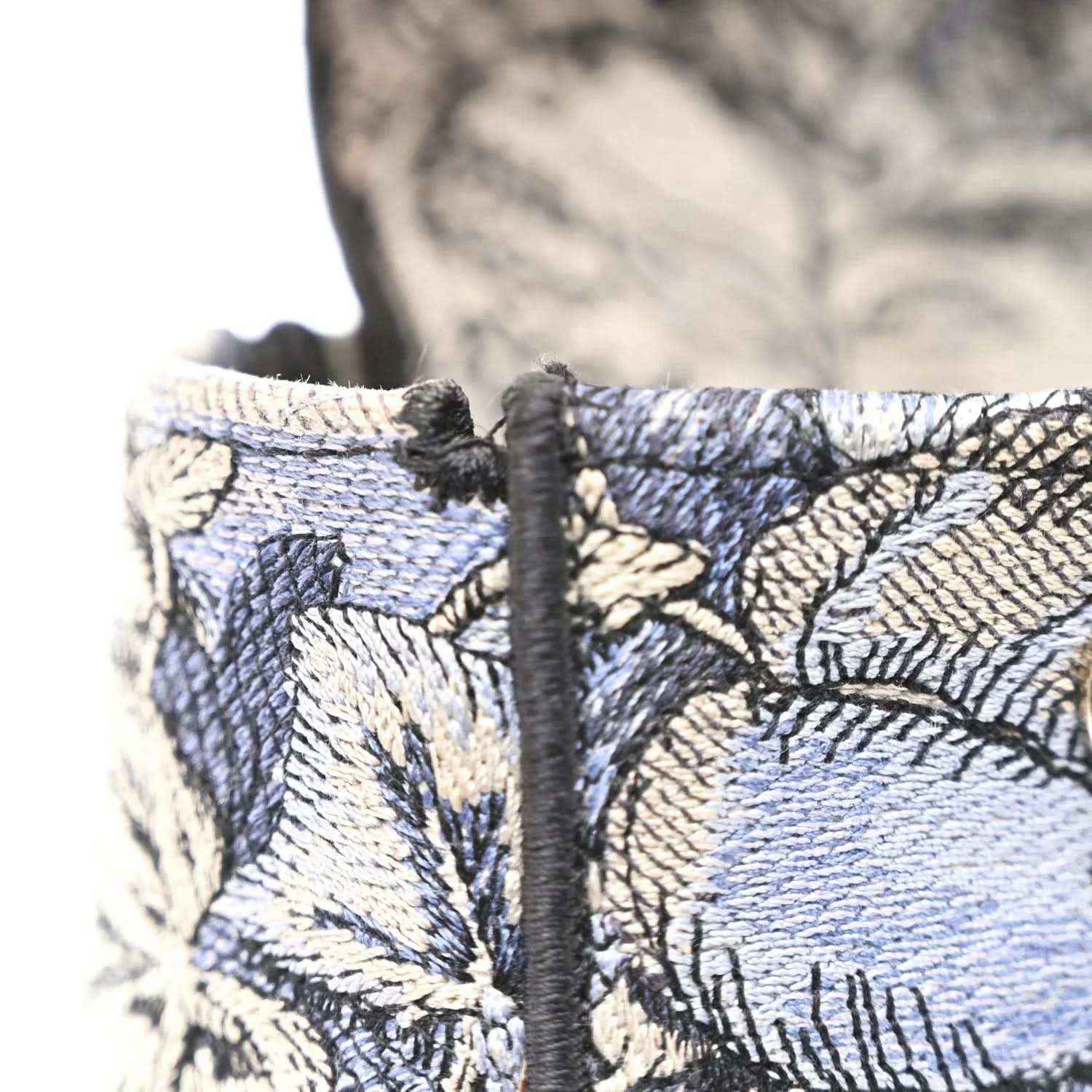 Embroidered denim bag corner with braided trim and dark strap