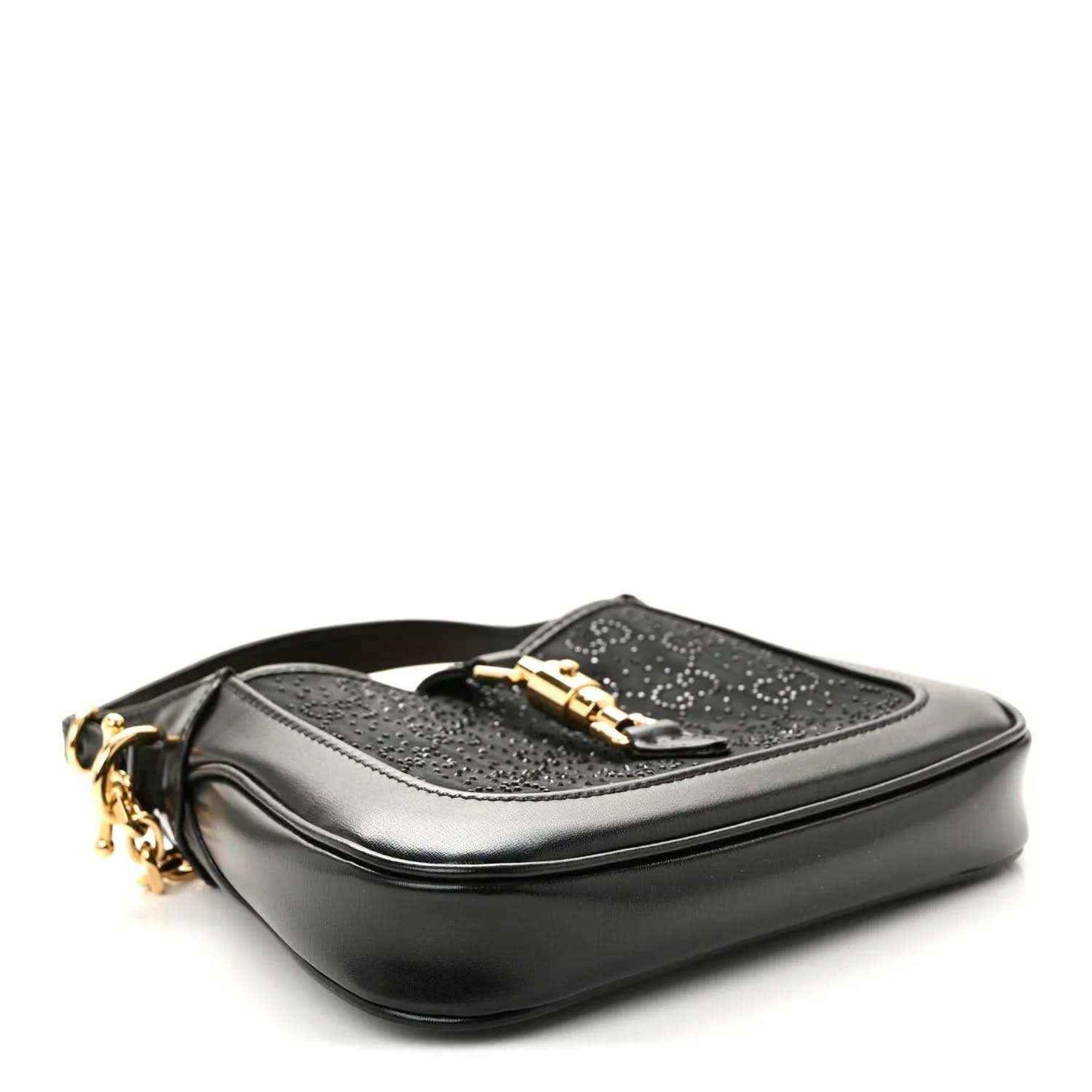 Black hobo bag with gold hardware and a top flap clasp, side view.