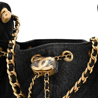 Black mini handbag with gold chain straps and CC-like charm at center