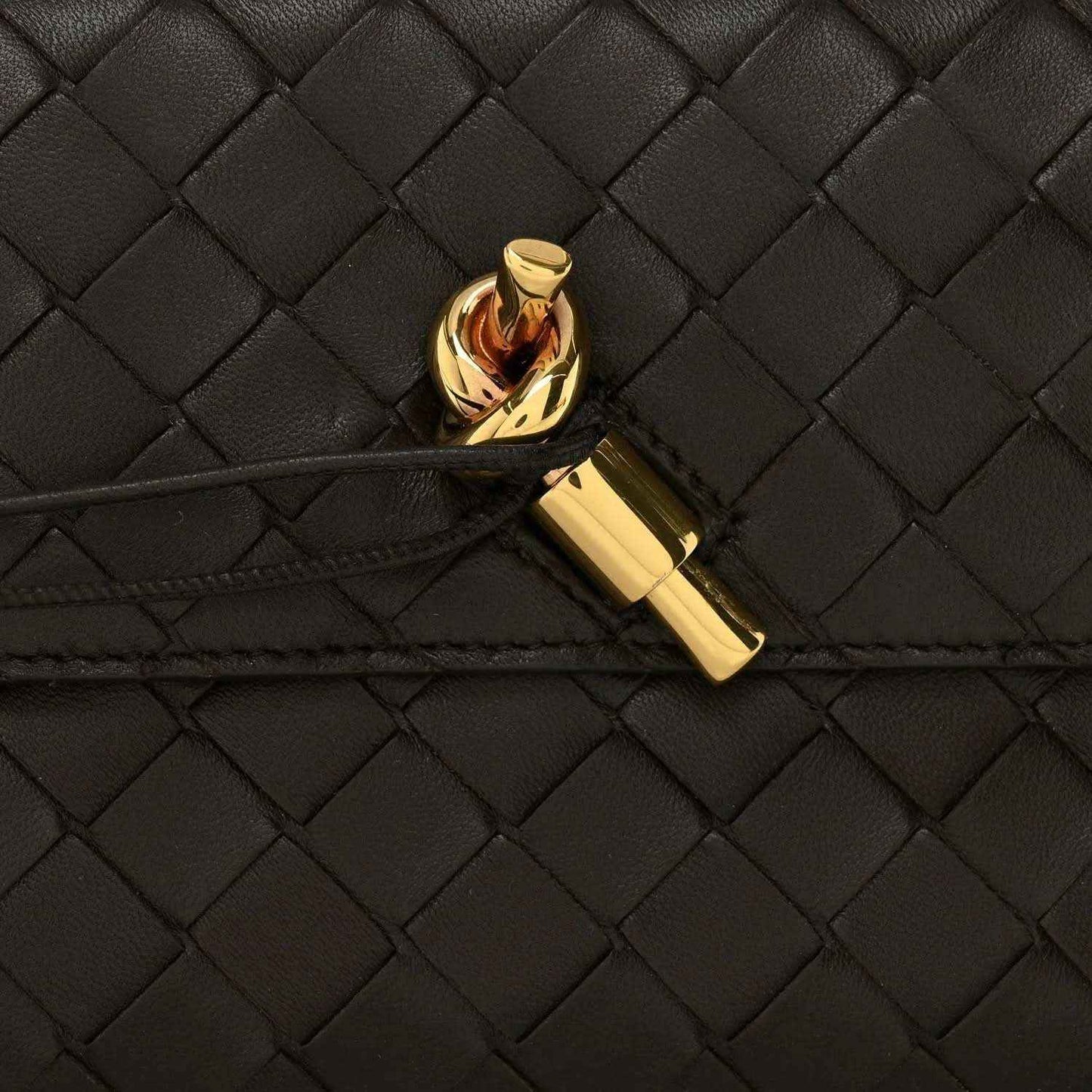 Gold clasp on black intrecciato woven leather clutch flap