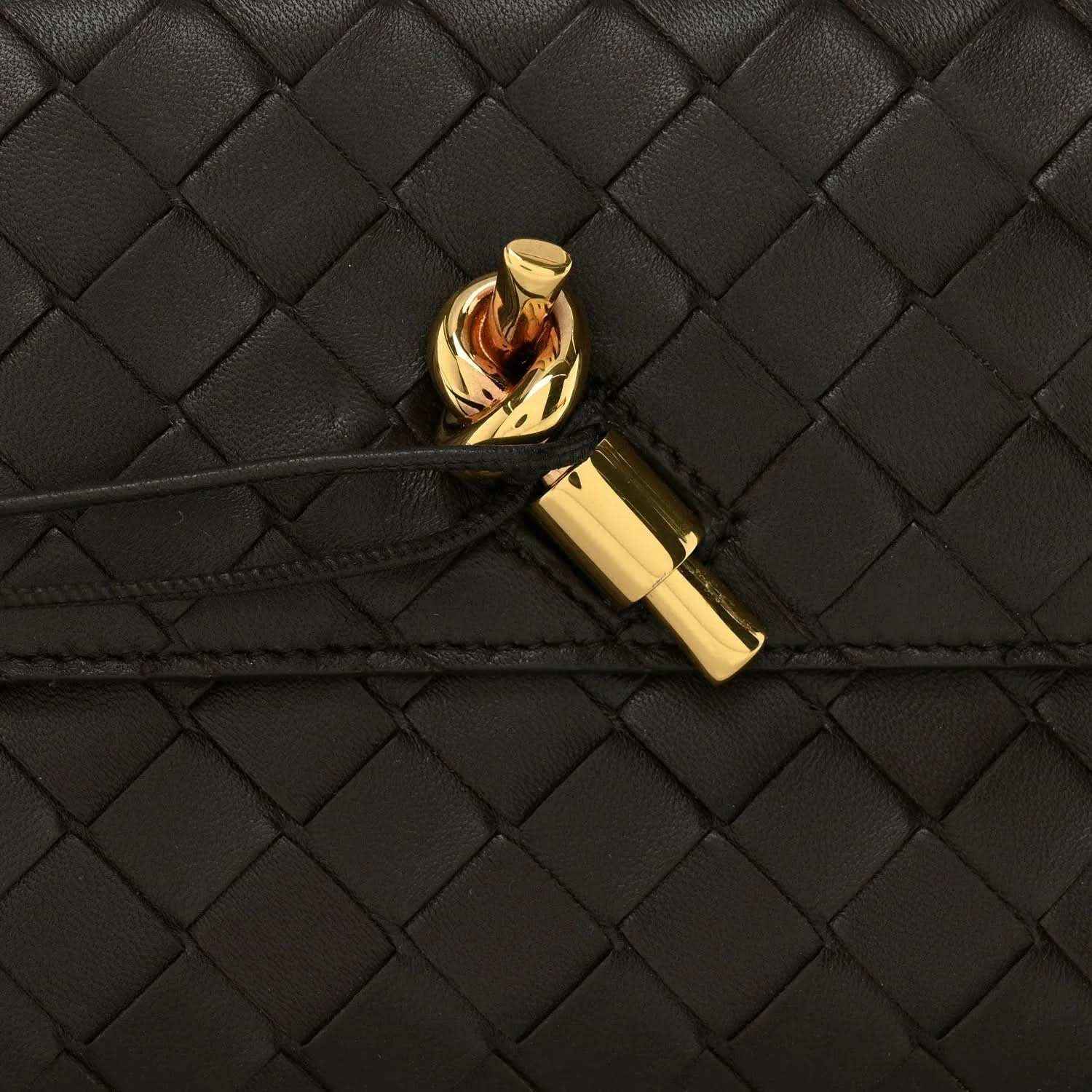 Gold clasp on black intrecciato woven leather clutch flap