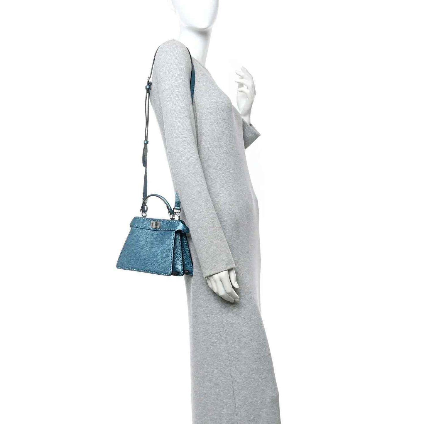 Blue leather mini satchel worn crossbody with top handle and thin shoulder strap.