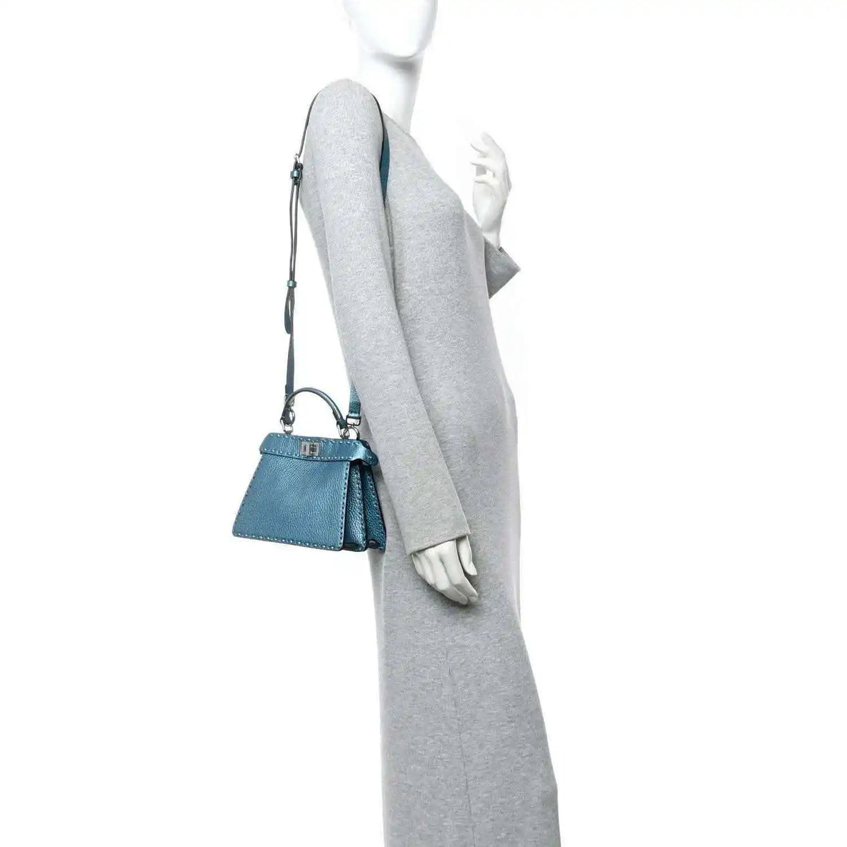 Blue leather mini satchel worn crossbody with top handle and thin shoulder strap.