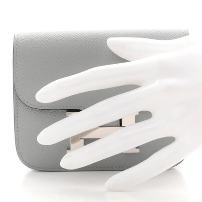 Hermes Constance slim wallet, light blue textured leather, open flap with H clasp.