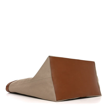 Beige canvas tote bag with brown leather top panel and structured base