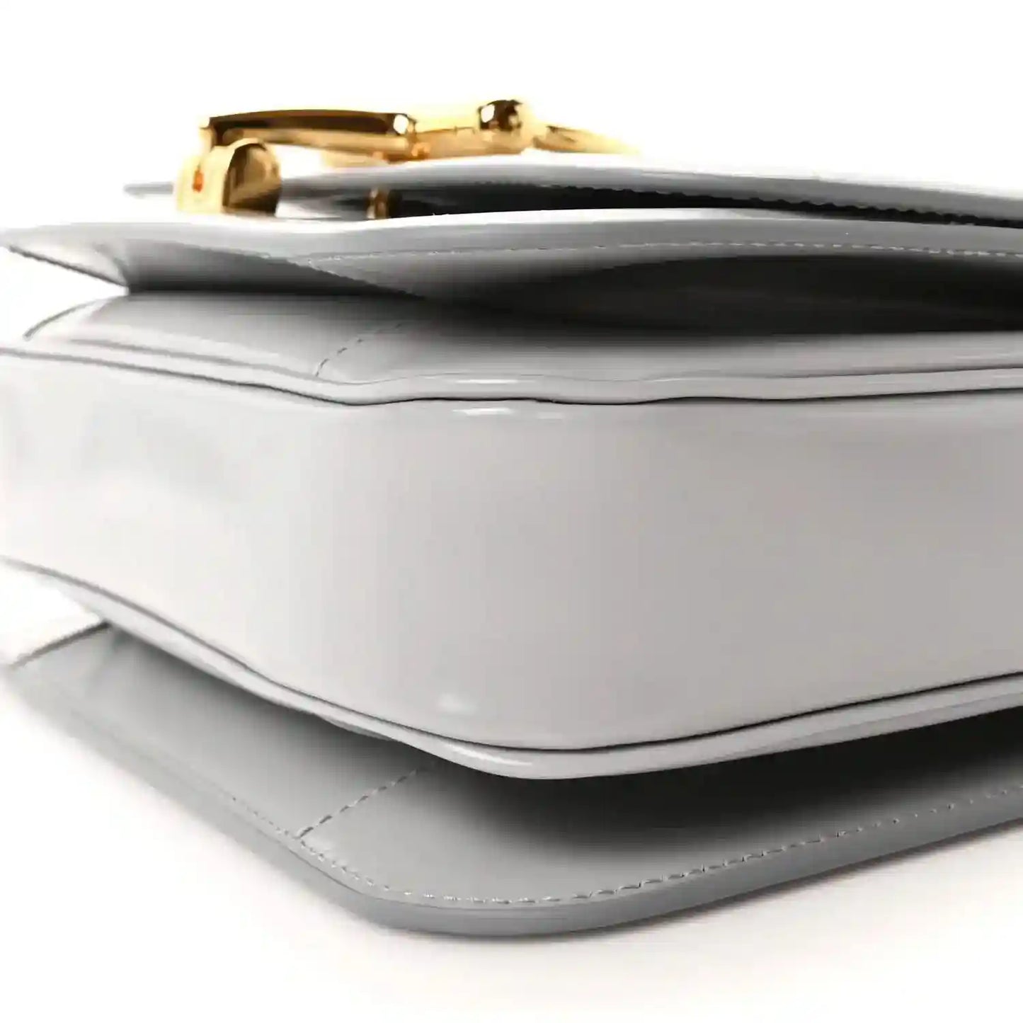 Light grey small shoulder bag corner detail with gold-tone clasp and stitched trim