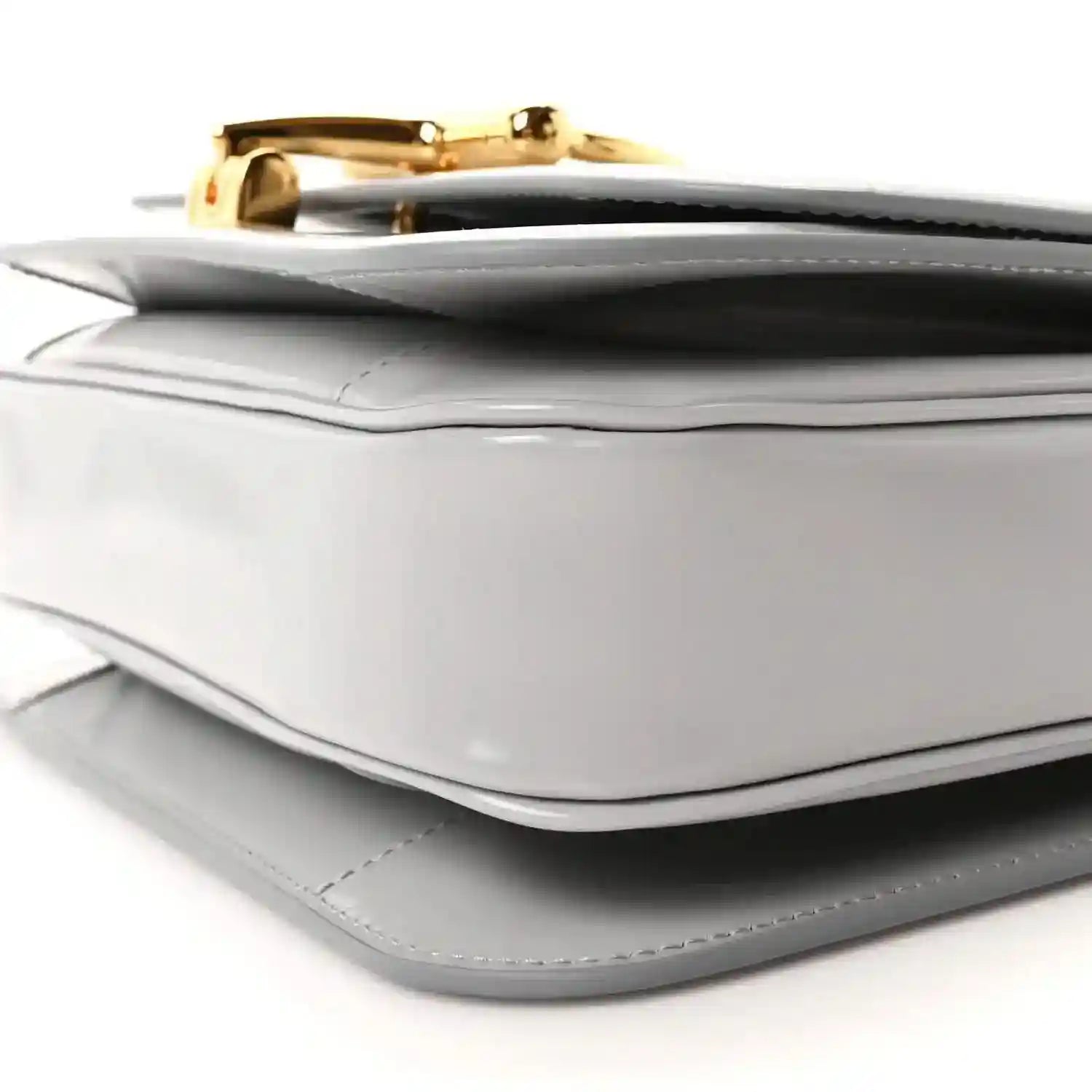 Light grey small shoulder bag corner detail with gold-tone clasp and stitched trim