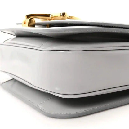 Light grey small shoulder bag corner detail with gold-tone clasp and stitched trim
