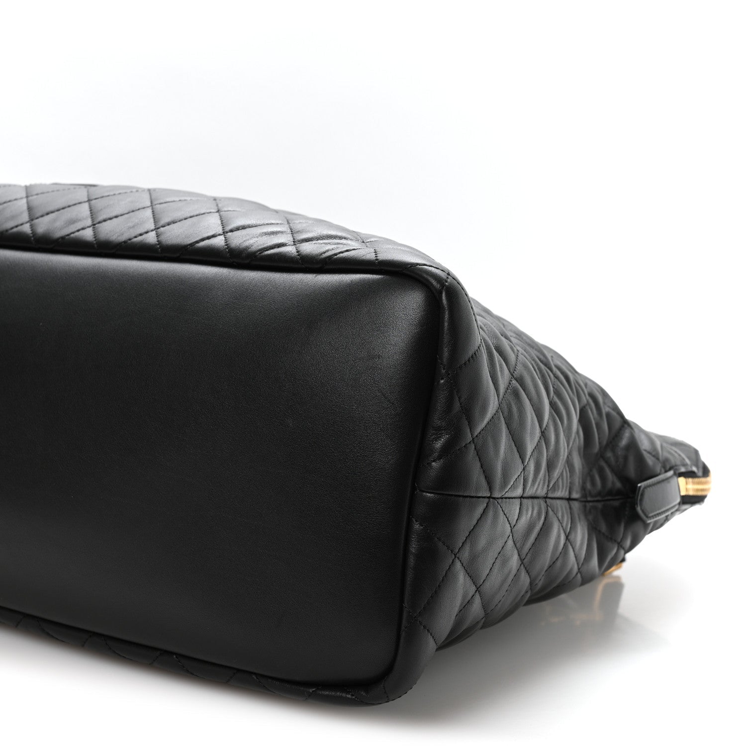 Black quilted leather travel bag corner with smooth base panel and gold hardware