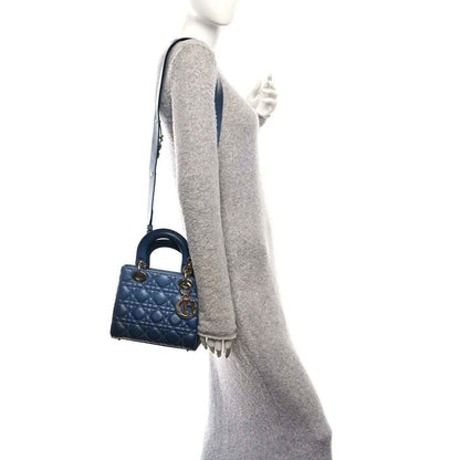 Small quilted indigo blue leather handbag worn crossbody with strap and gold clasp