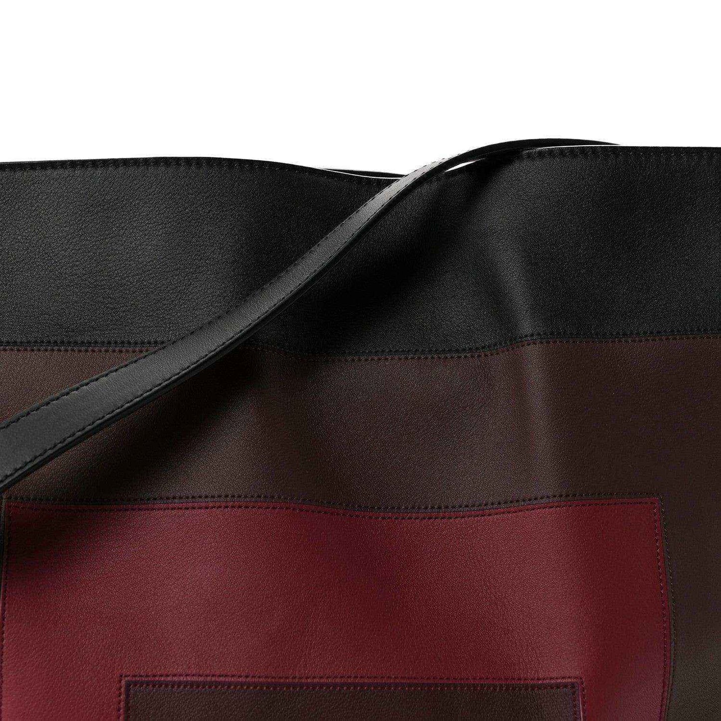 Clutch bag front close-up: black strap and burgundy logo patch panel