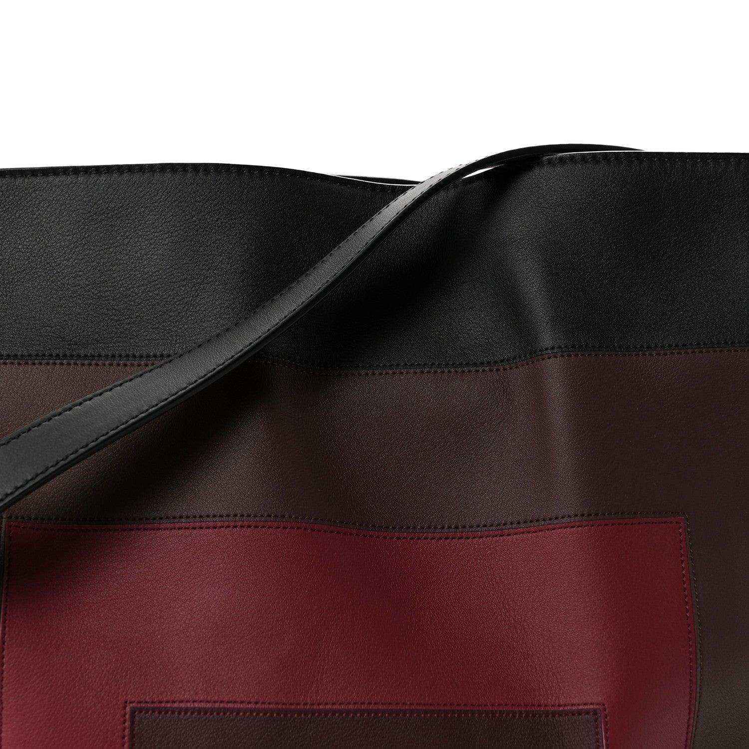 Clutch bag front close-up: black strap and burgundy logo patch panel