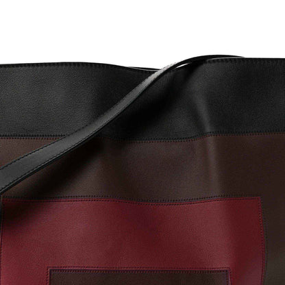Clutch bag front close-up: black strap and burgundy logo patch panel