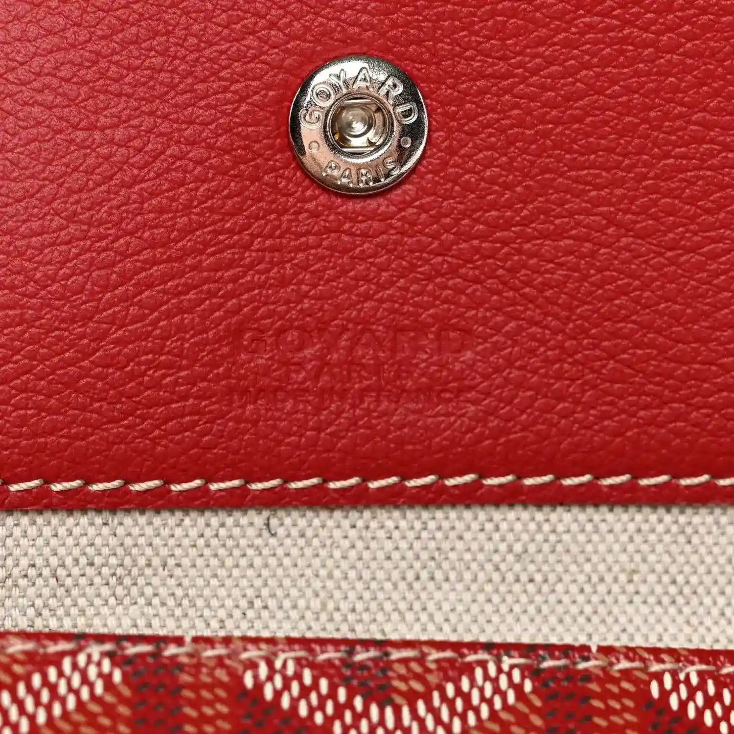 Red Goyardine bag exterior with round silver snap stud