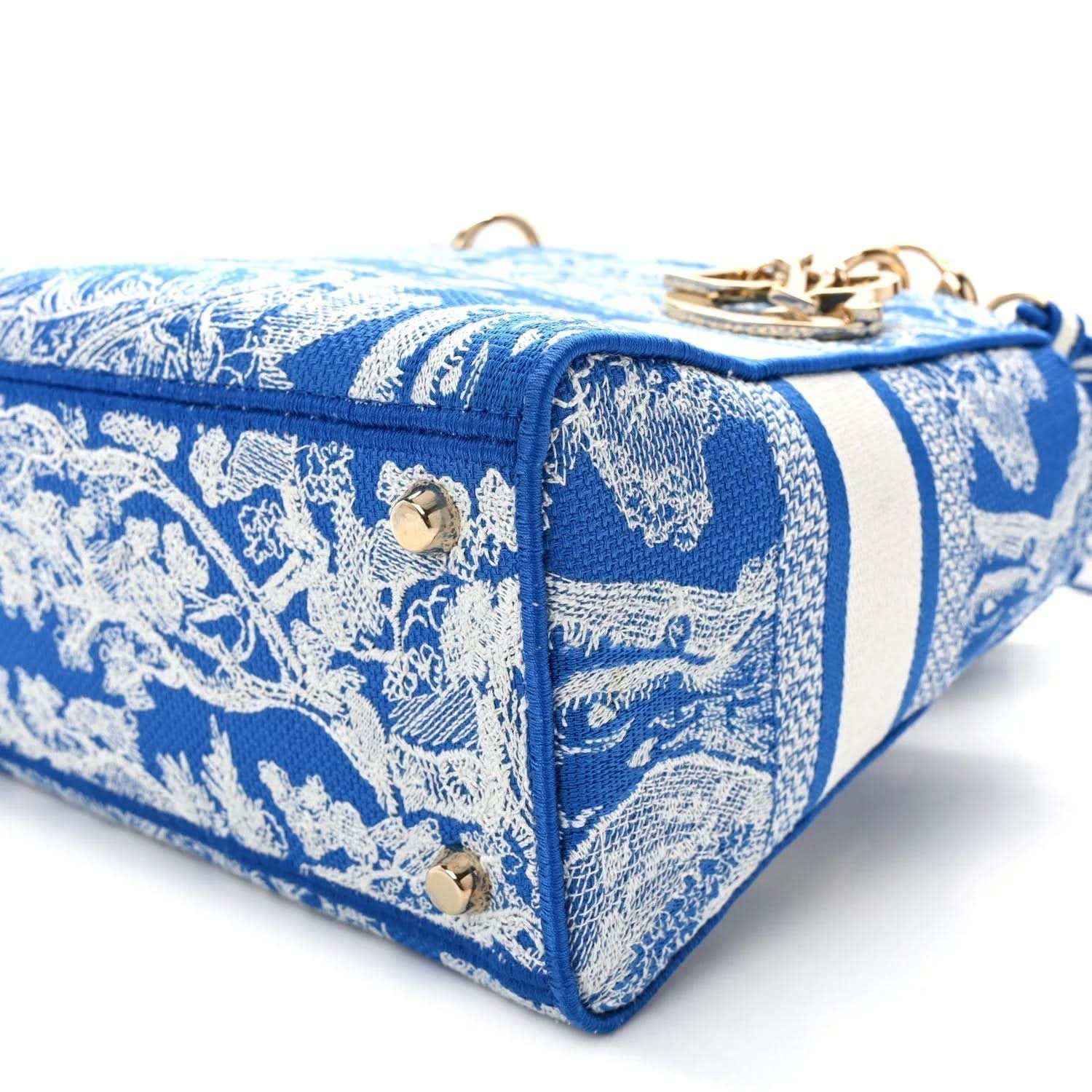 Blue toile handbag with white striped trim, gold studs, and top zipper