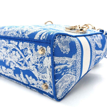 Blue toile handbag with white striped trim, gold studs, and top zipper