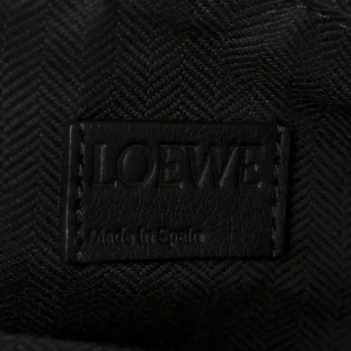 Black leather brand label on small raffia puzzle bag interior