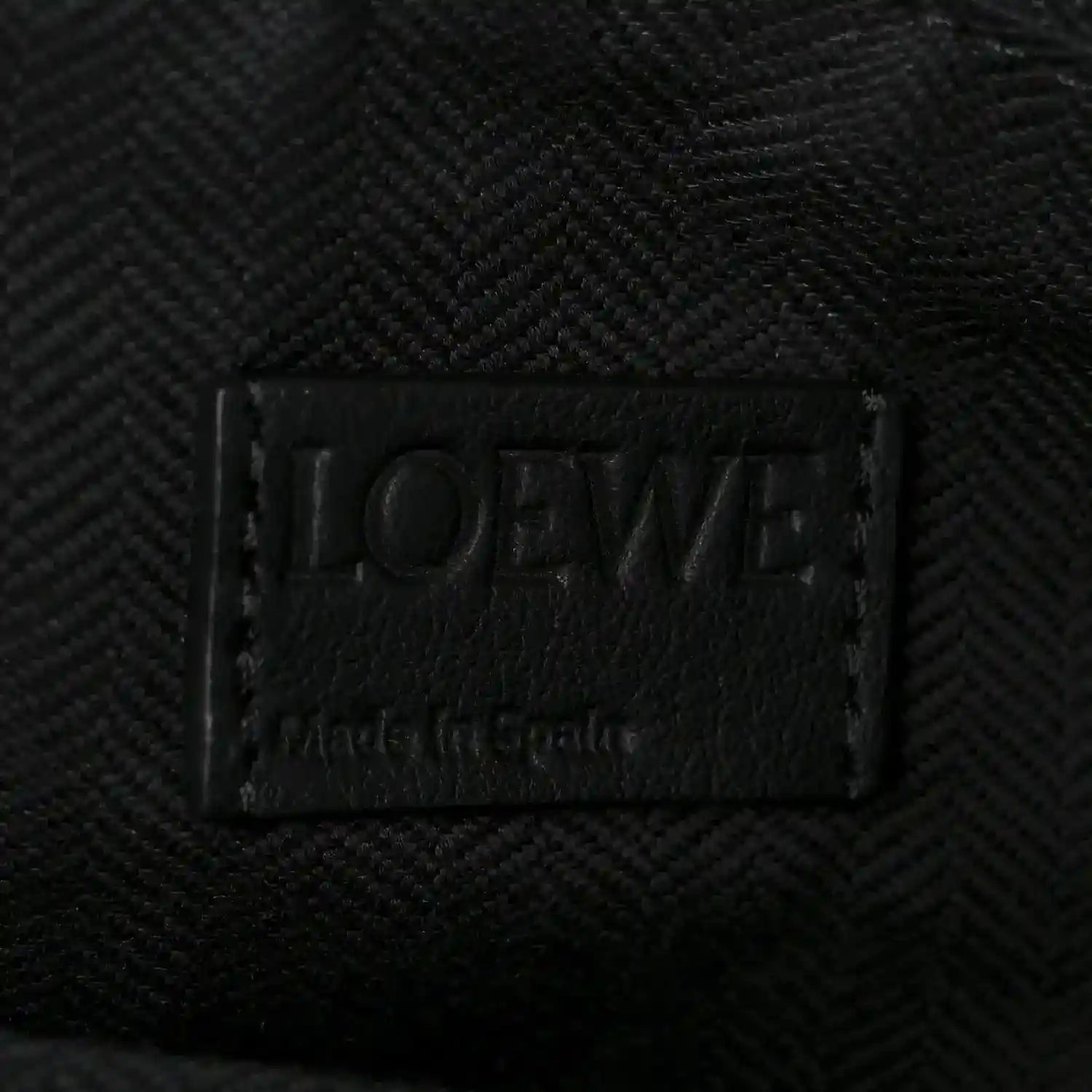 Black leather brand label on small raffia puzzle bag interior