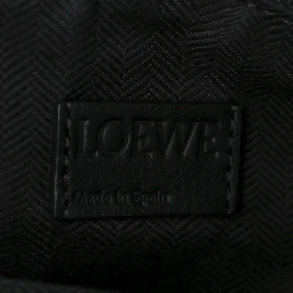 Black leather brand label on small raffia puzzle bag interior