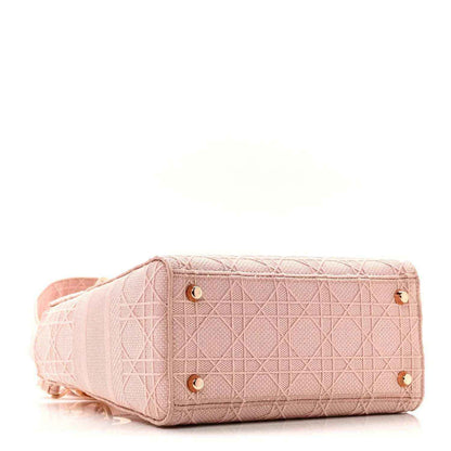 Pink canvas bag with top flap, gold studs, and braided-look strap