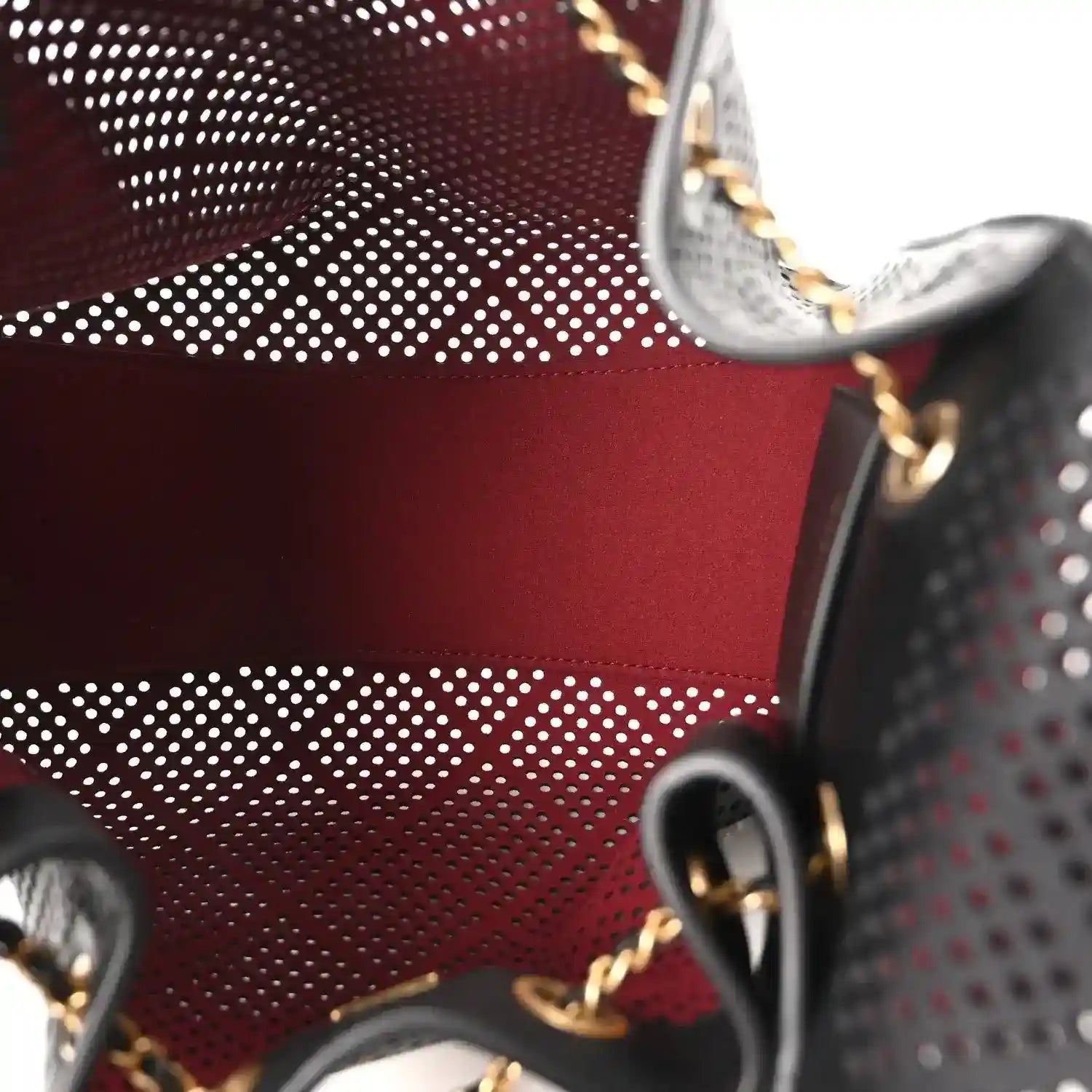 Small black perforated handbag with red lining and gold chain hardware