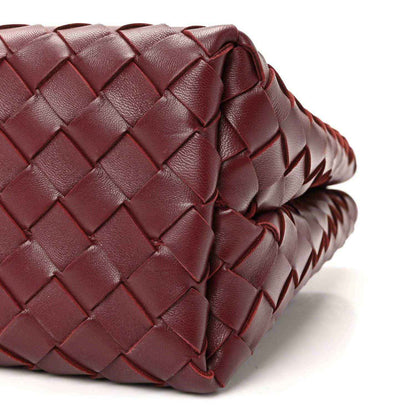 Burgundy intrecciato nappa leather bag corner with braided trim detail.