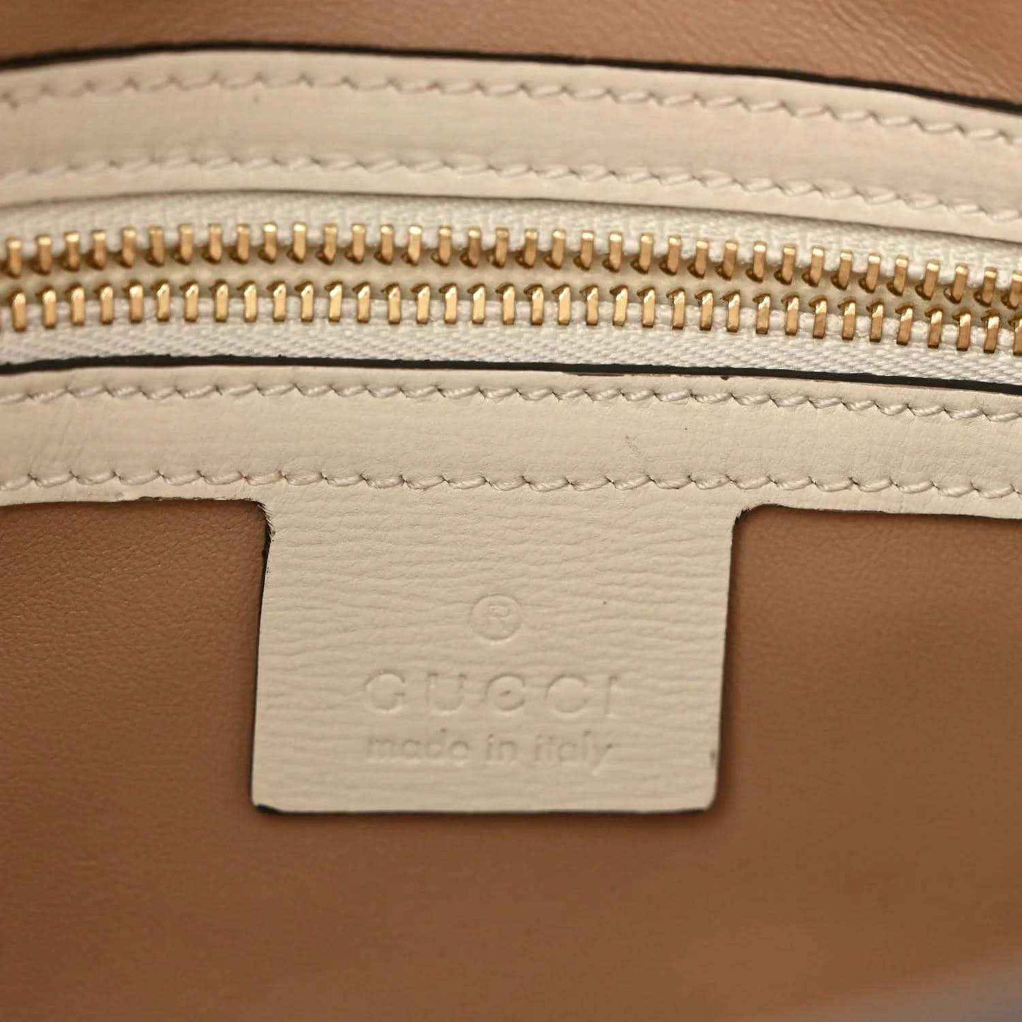 Leather interior label with gold zipper teeth and stitched seam detail.