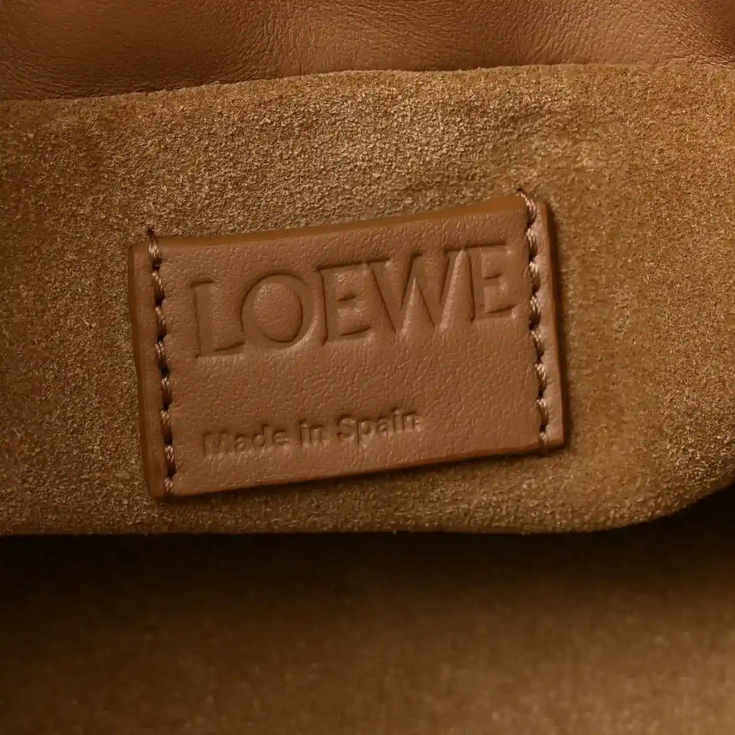 Tan leather mini clutch with embossed LOEWE and "Made in Spain" label.