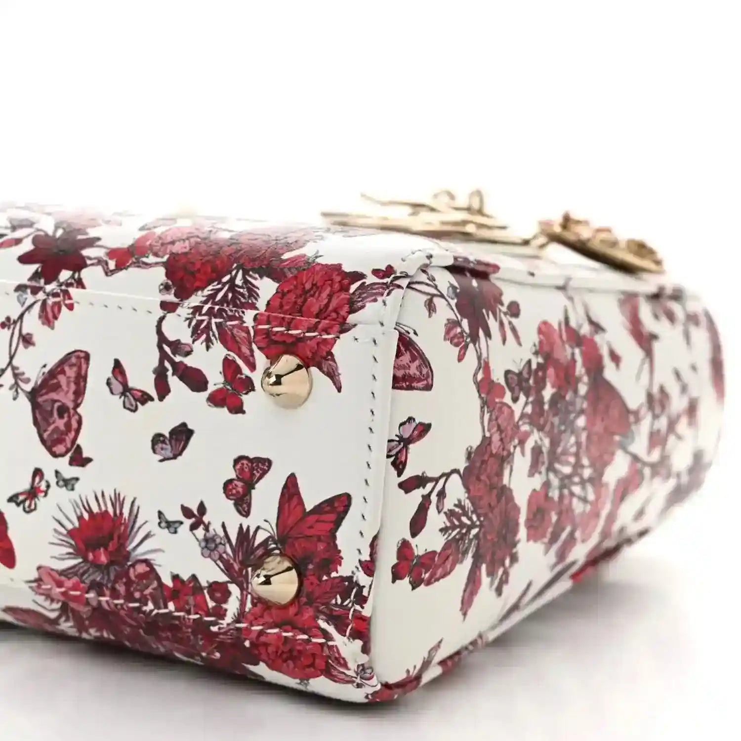 Side view of small handbag with white-red floral print, gold hardware, and zip top edge