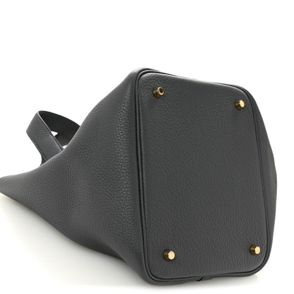 Dark gray leather handbag with gold-toned studs on front panel and angled base