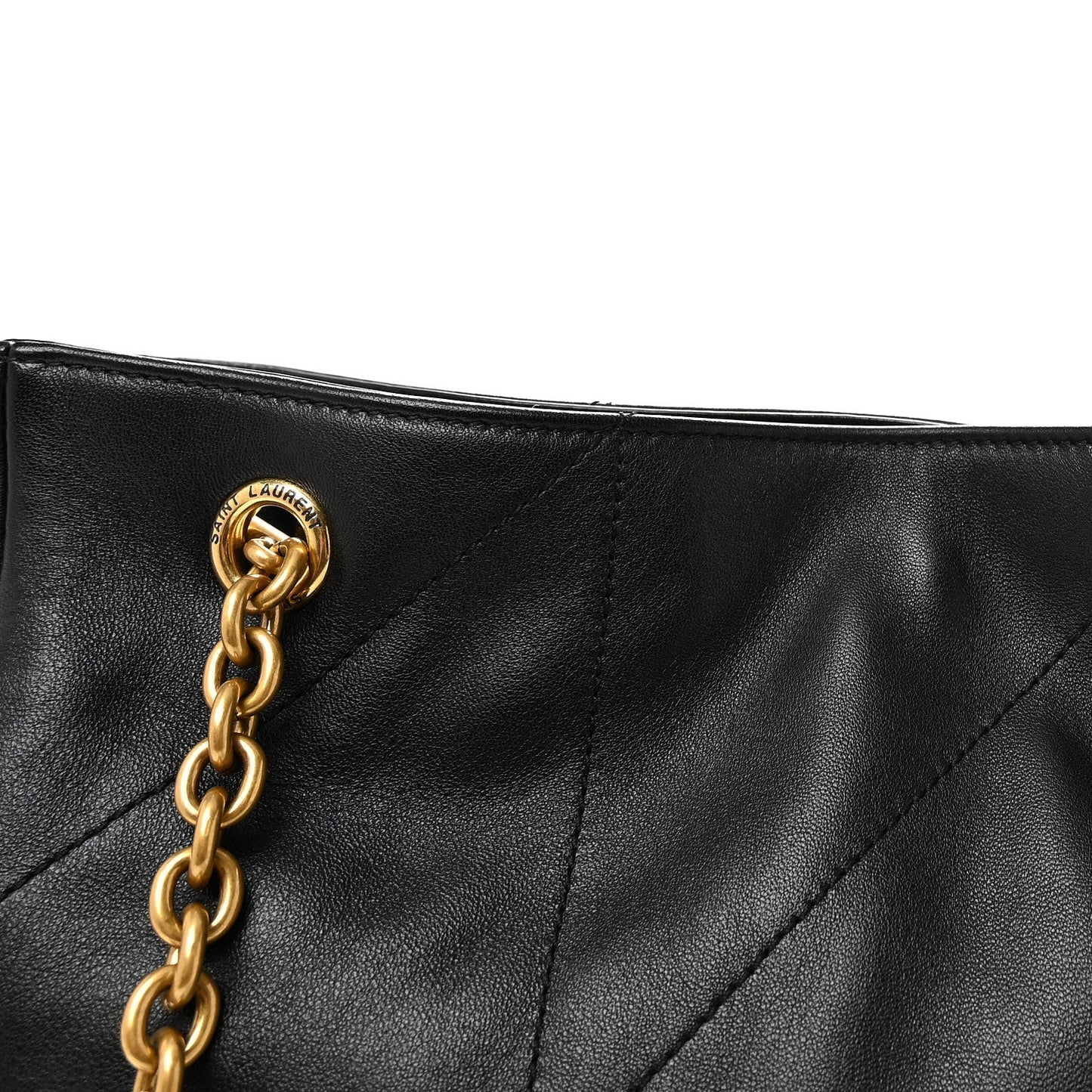 Black quilted tote top corner with gold chain link handle and stitched seam lines.