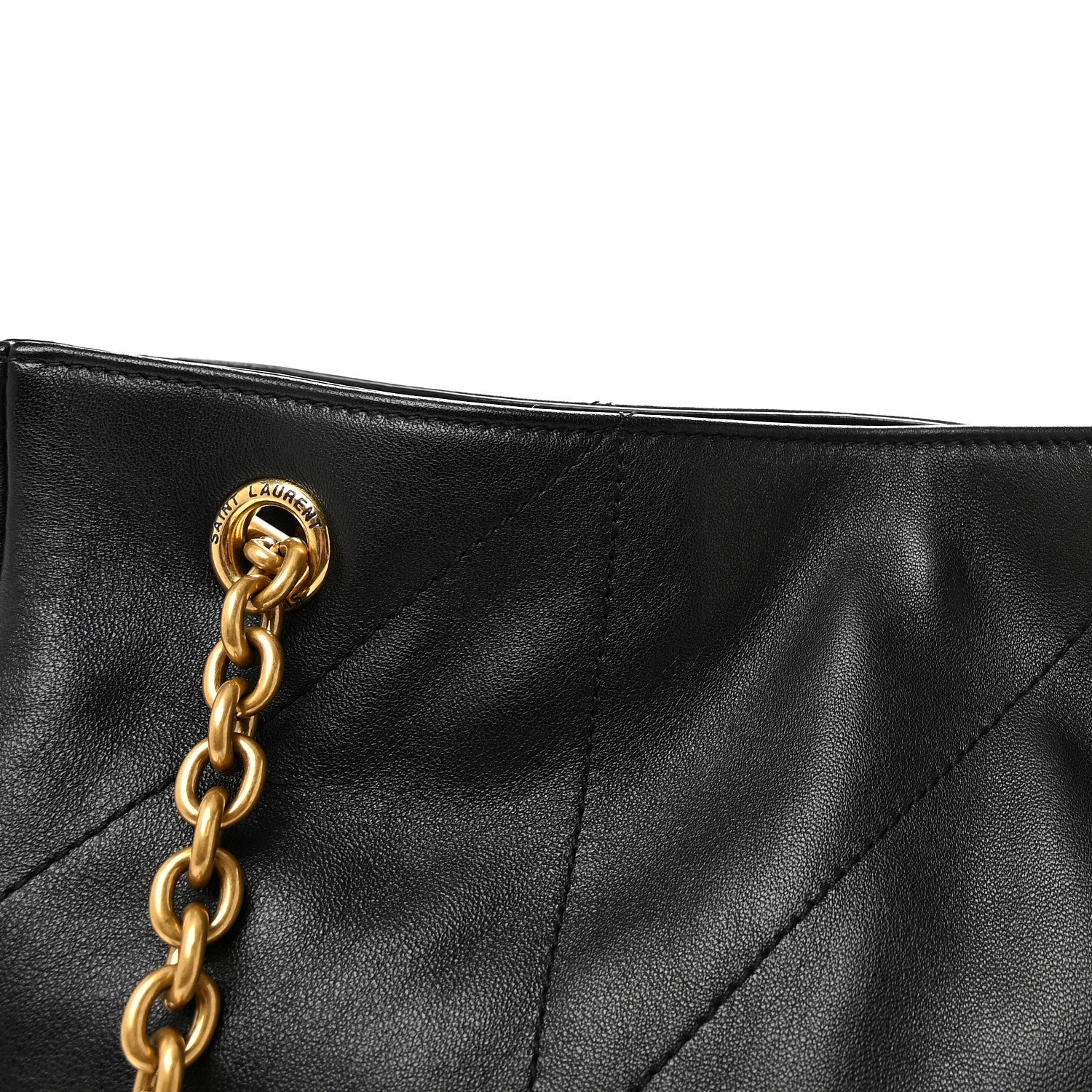 Black quilted tote top corner with gold chain link handle and stitched seam lines.