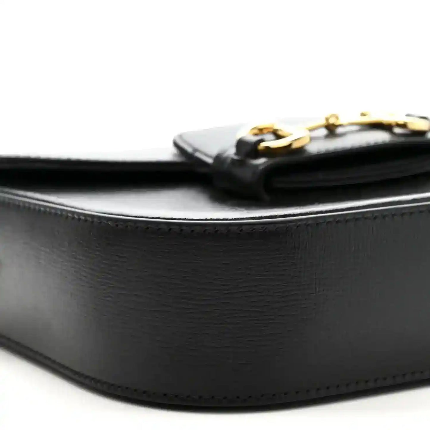 Close-up of black leather side and top edge with gold-tone hardware on mini bag
