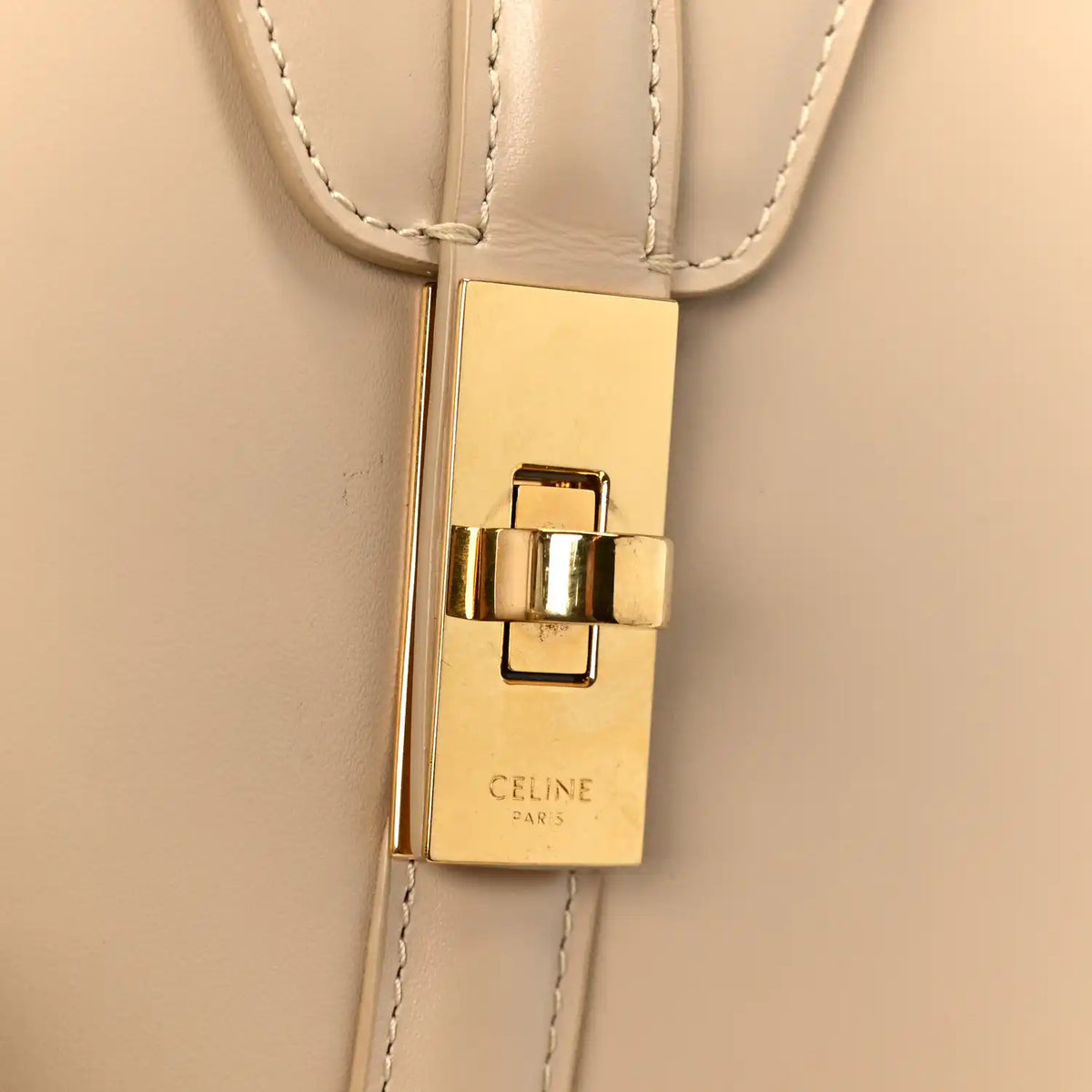 Gold-tone clasp with Celine Paris logo plate on nude leather strap attachment