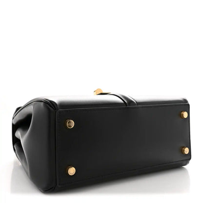 Black structured tote-style bag with top handle and gold snaps on front panel