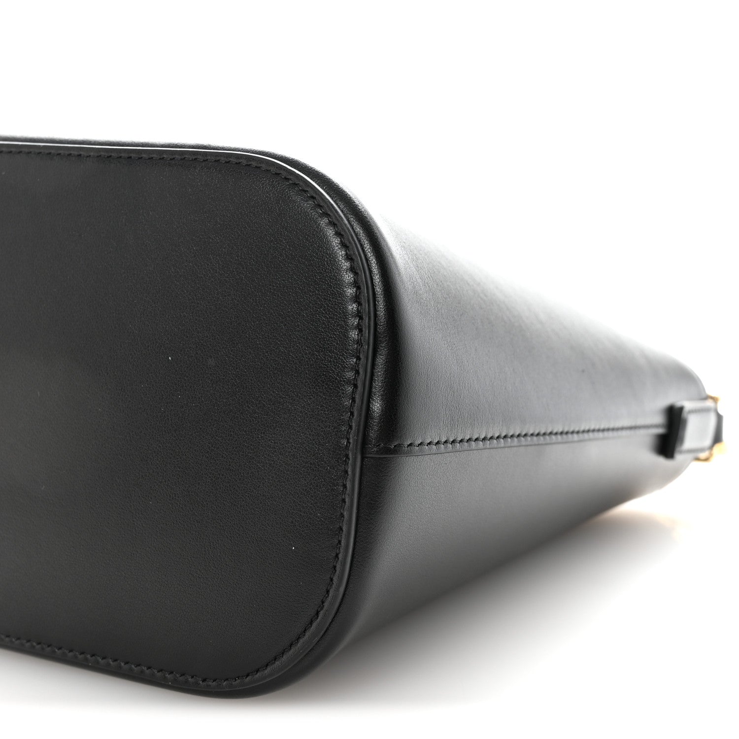Close-up of black leather bag corner with stitching and gold-tone clasp hardware