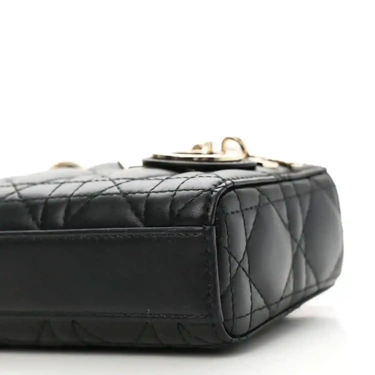 Black quilted lambskin micro handbag with top clasp and side stitching, close-up