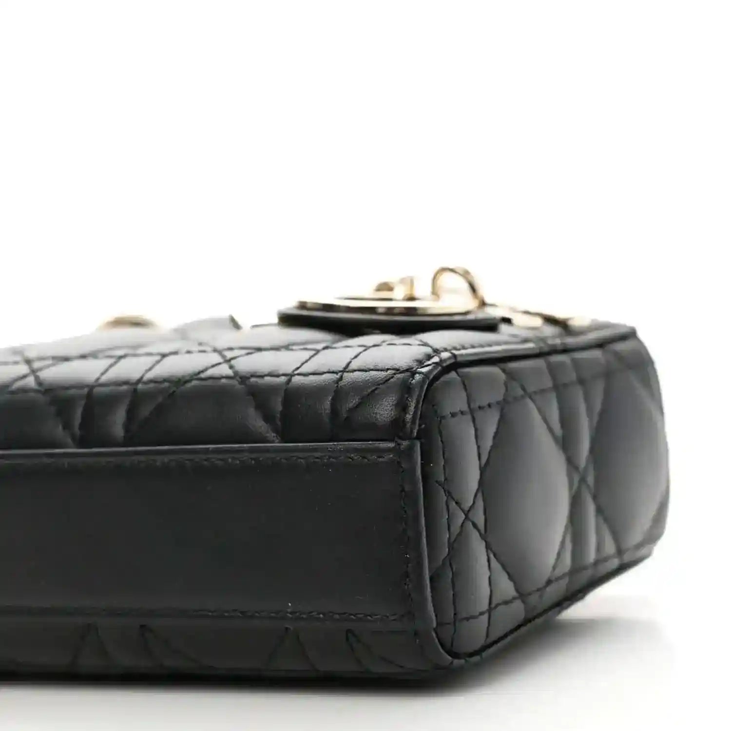 Black quilted lambskin micro handbag with top clasp and side stitching, close-up