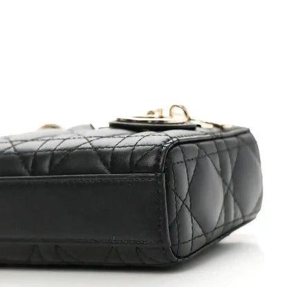 Black quilted lambskin micro handbag with top clasp and side stitching, close-up